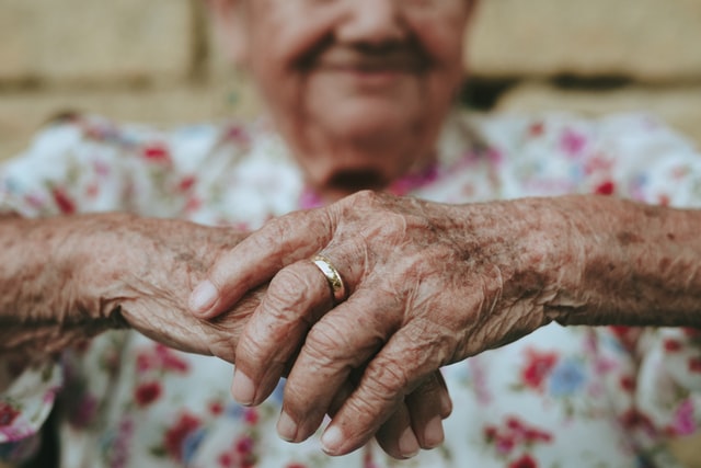 Elderly woman sitting with hands crossed depicting age and mental wellness